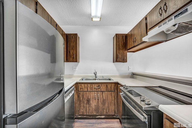 kitchen with a textured ceiling, sink, and stainless steel appliances