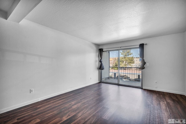 empty room with a textured ceiling and dark hardwood / wood-style flooring