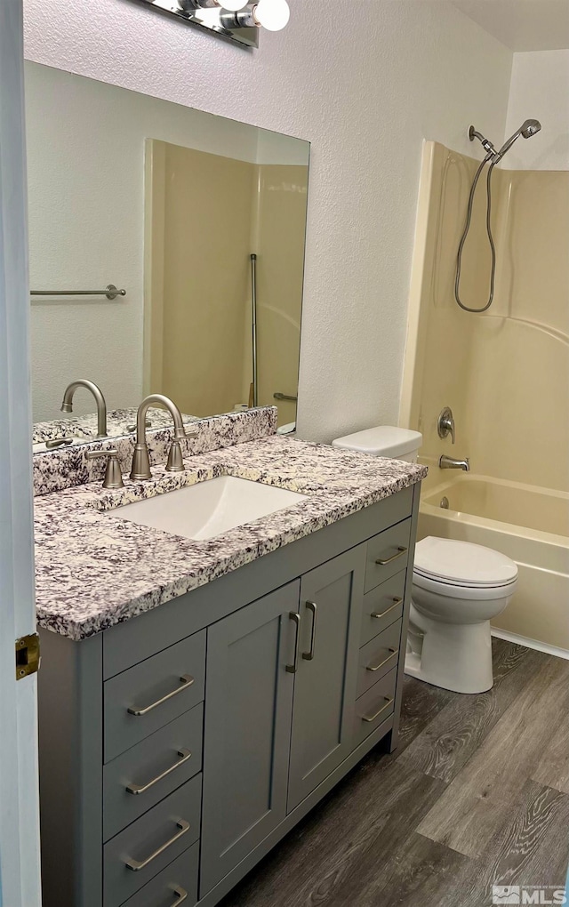 full bathroom with vanity, wood-type flooring, shower / tub combination, and toilet