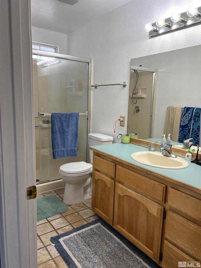 bathroom with vanity, tile patterned floors, toilet, a shower with door, and a textured ceiling