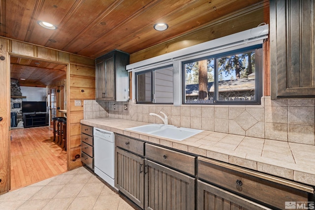 kitchen with tile countertops, dishwasher, sink, light tile patterned floors, and dark brown cabinetry