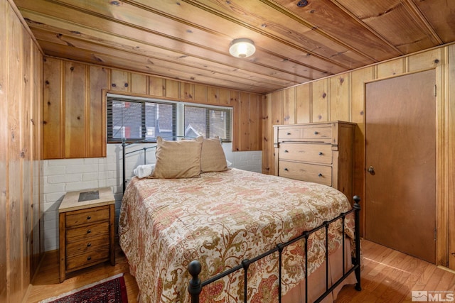 bedroom with wood walls, light hardwood / wood-style floors, and wood ceiling