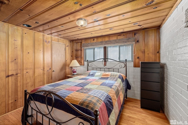 bedroom featuring wood walls, light wood-type flooring, brick wall, and wooden ceiling