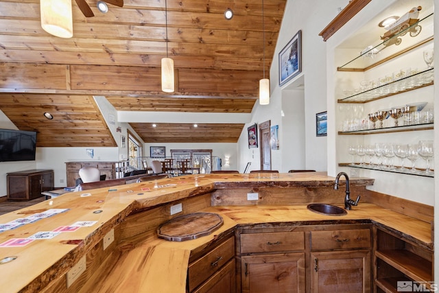 kitchen featuring wooden counters, wood ceiling, sink, decorative light fixtures, and vaulted ceiling with beams