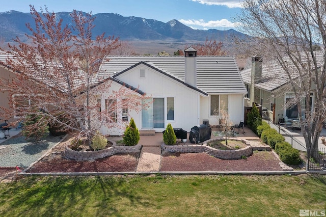 rear view of house with a mountain view, a yard, and a patio