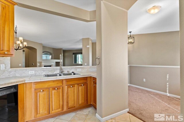 kitchen with tasteful backsplash, black dishwasher, light colored carpet, sink, and pendant lighting