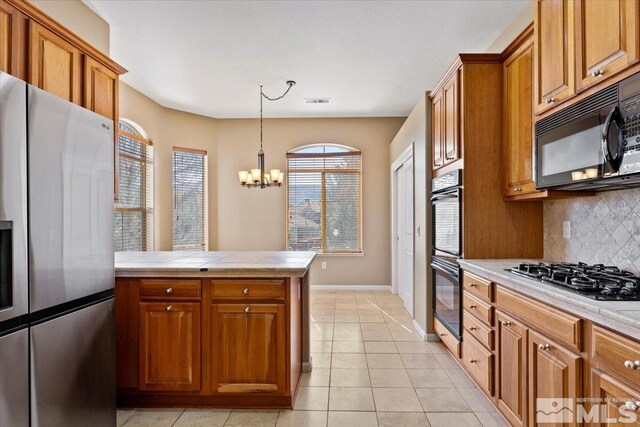 kitchen featuring decorative light fixtures, a chandelier, light tile flooring, backsplash, and black appliances