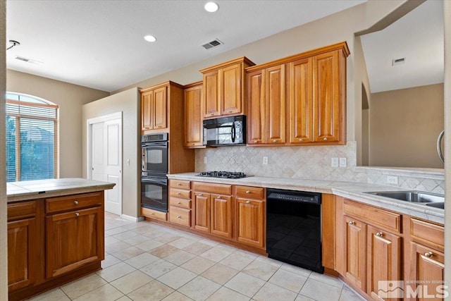 kitchen with tile countertops, tasteful backsplash, black appliances, and light tile floors