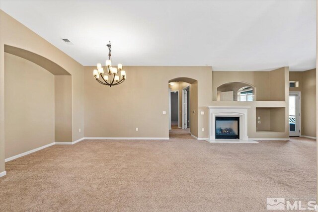 unfurnished living room with a notable chandelier and carpet floors