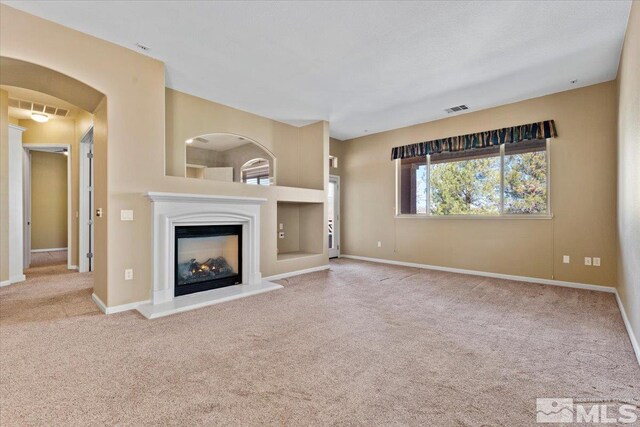 unfurnished living room featuring a multi sided fireplace and carpet floors