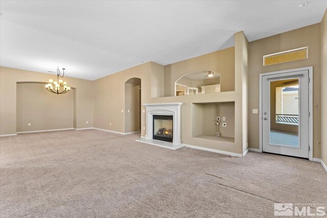 unfurnished living room featuring carpet flooring, a notable chandelier, and built in shelves