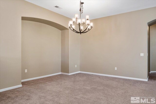 empty room with carpet floors and an inviting chandelier