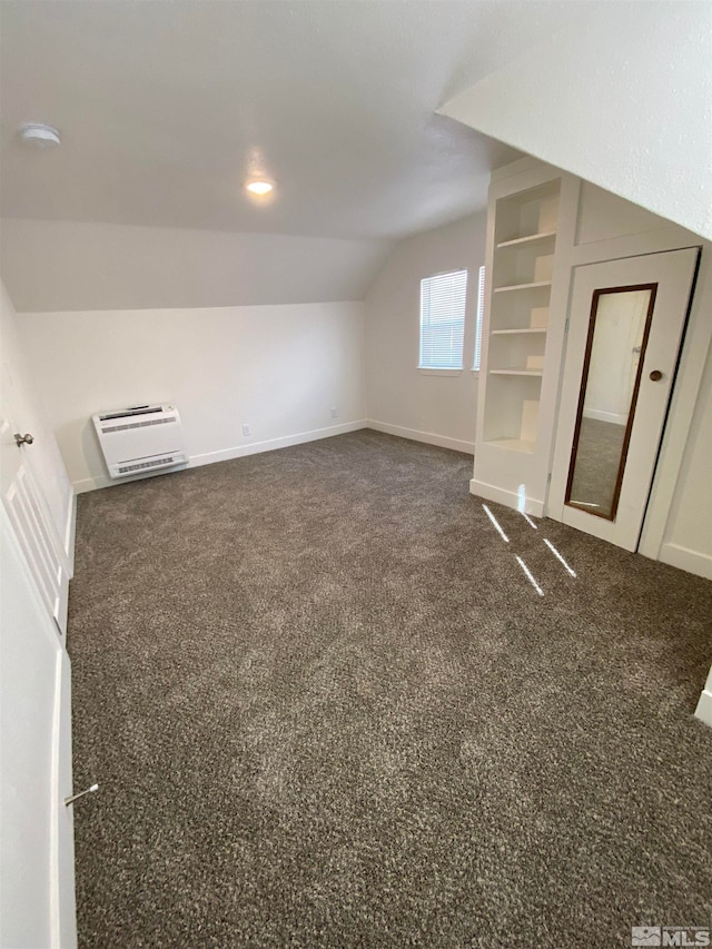 additional living space with built in features, lofted ceiling, and dark colored carpet