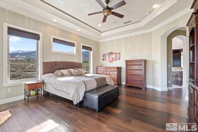 bedroom featuring ceiling fan, crown molding, dark hardwood / wood-style floors, a tray ceiling, and connected bathroom