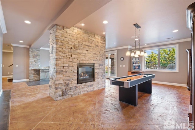 recreation room with ornamental molding, dark tile flooring, and a stone fireplace