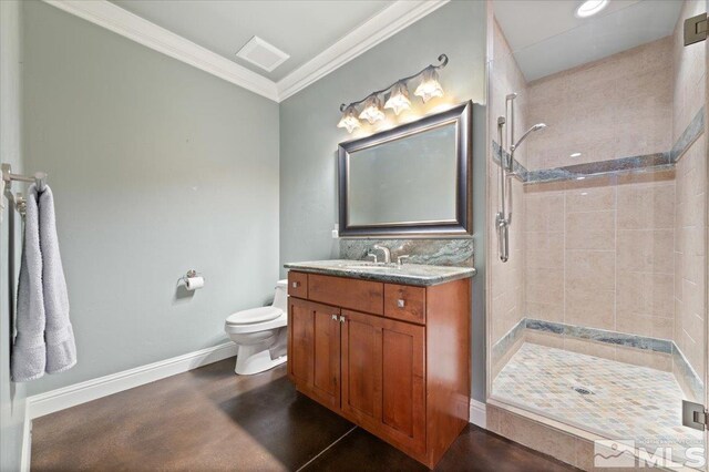 bathroom featuring large vanity, tiled shower, toilet, and ornamental molding