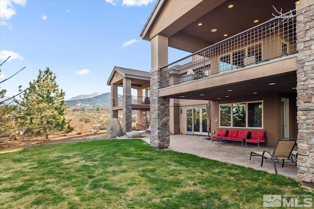 exterior space with a mountain view, a balcony, a yard, and a patio area