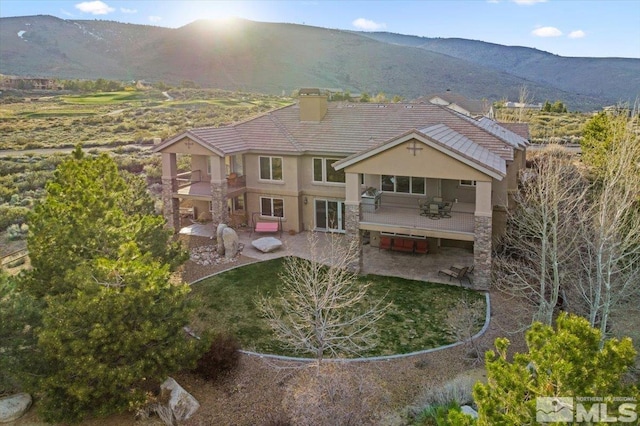 back of property featuring a mountain view and a patio