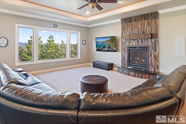 carpeted living room with ornamental molding, ceiling fan, a brick fireplace, and a tray ceiling