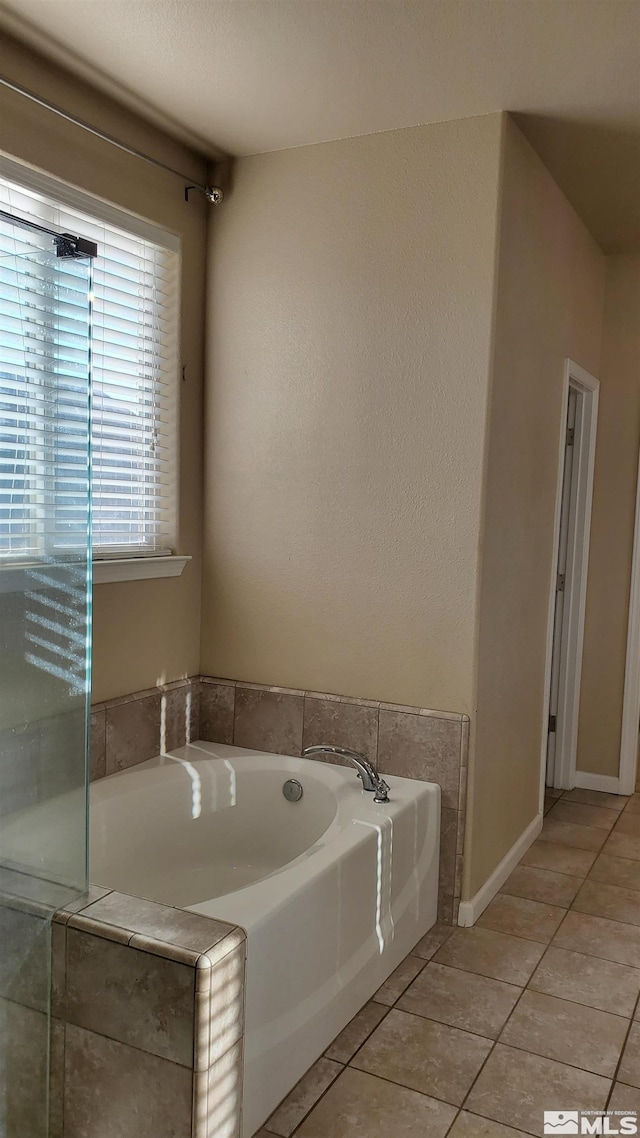 bathroom featuring a bath to relax in and tile floors