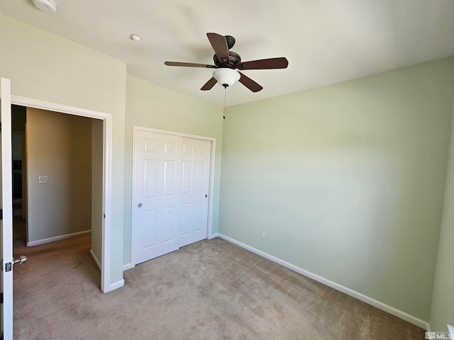 unfurnished bedroom featuring light colored carpet, a closet, and ceiling fan