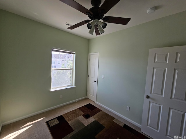 empty room with dark carpet and ceiling fan