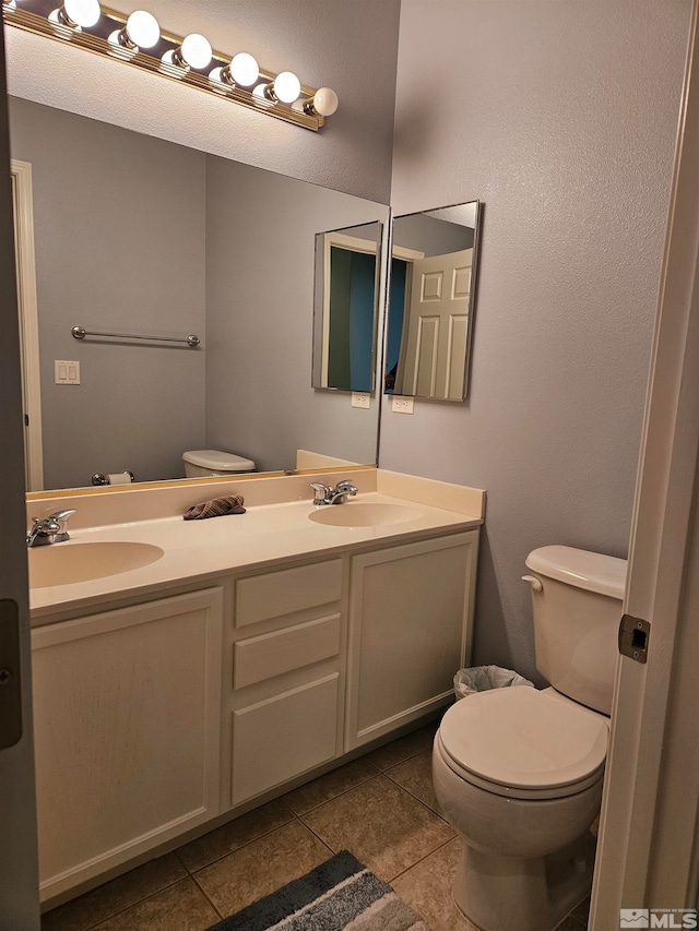 bathroom with double vanity, toilet, and tile flooring