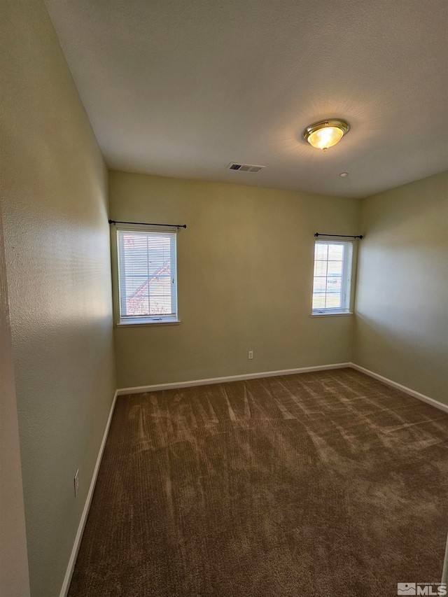 empty room featuring dark colored carpet