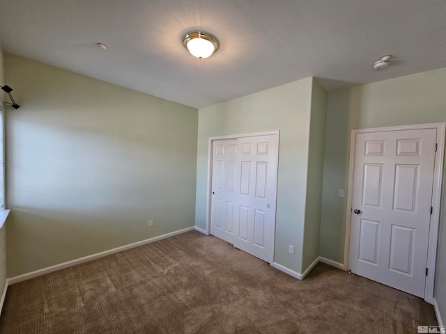 unfurnished bedroom with dark colored carpet and a closet