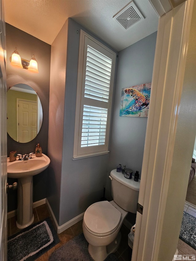 bathroom featuring tile flooring, toilet, and a textured ceiling