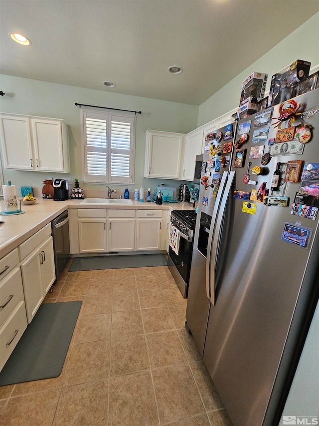 kitchen featuring light tile floors, stainless steel appliances, white cabinetry, and sink