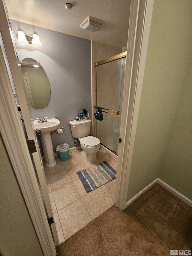 bathroom featuring tile flooring, a textured ceiling, sink, toilet, and a shower with door