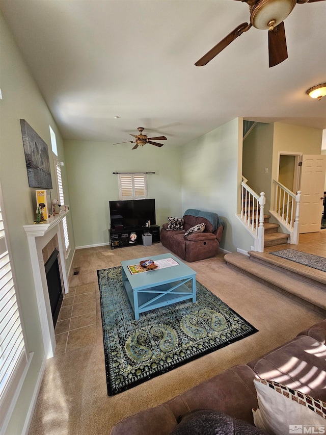 carpeted living room featuring a tile fireplace and ceiling fan