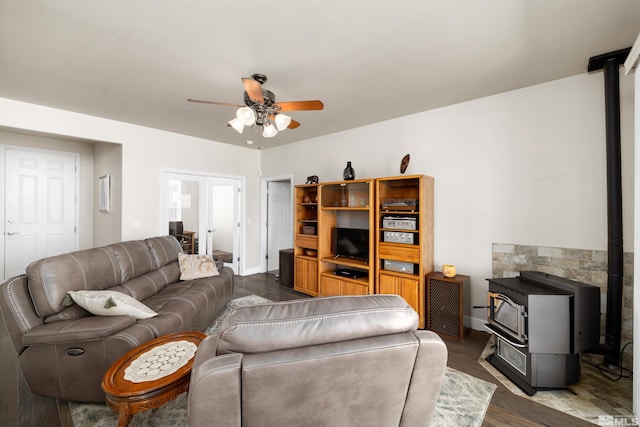 living room with wood-type flooring, ceiling fan, and a wood stove