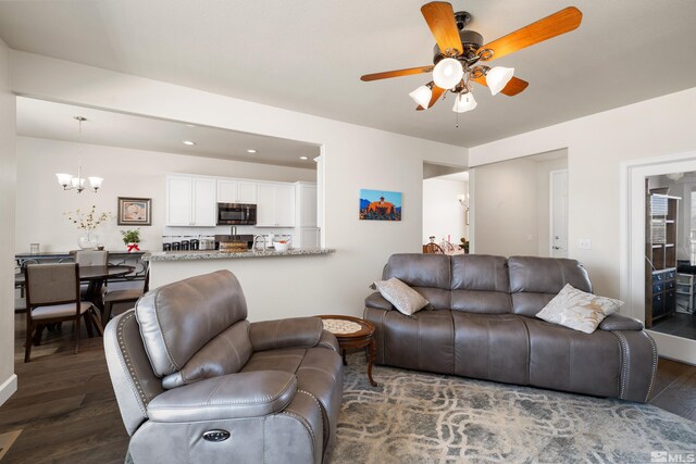 living room with dark hardwood / wood-style floors and ceiling fan with notable chandelier