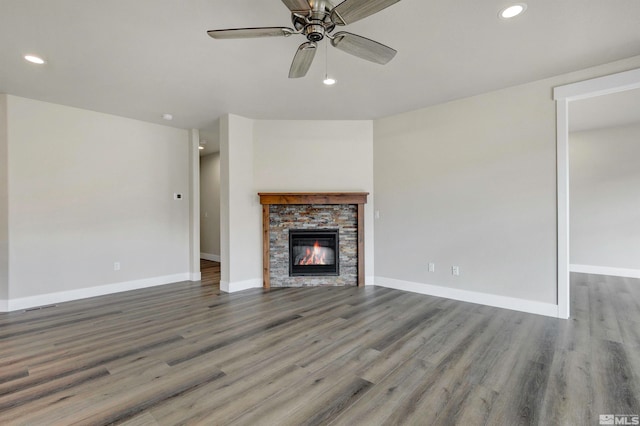 unfurnished living room featuring ceiling fan, a fireplace, and dark hardwood / wood-style floors