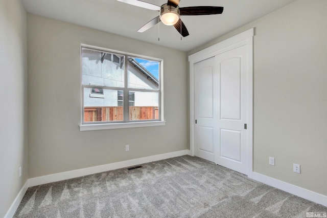 unfurnished bedroom featuring light colored carpet, ceiling fan, and a closet