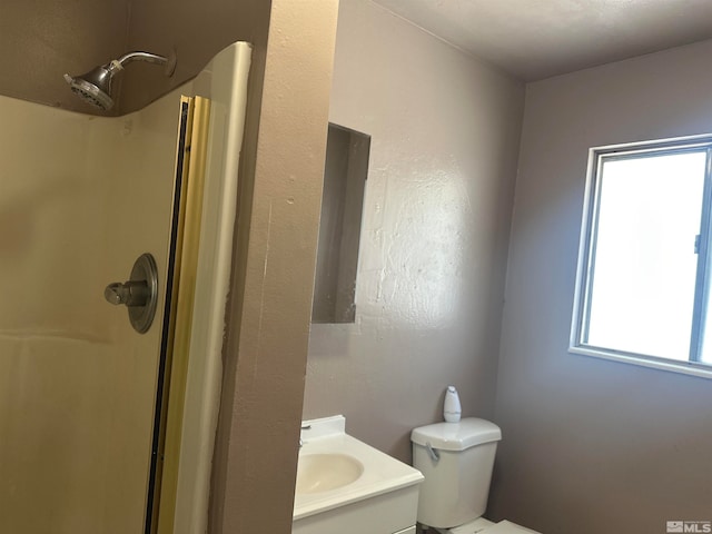 bathroom with walk in shower, plenty of natural light, vanity, and toilet