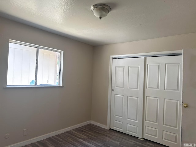 unfurnished bedroom with a closet and dark hardwood / wood-style floors