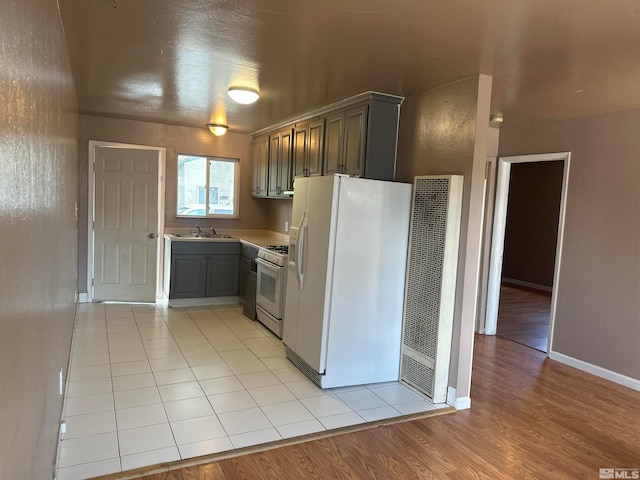 kitchen featuring sink, white appliances, and light tile flooring