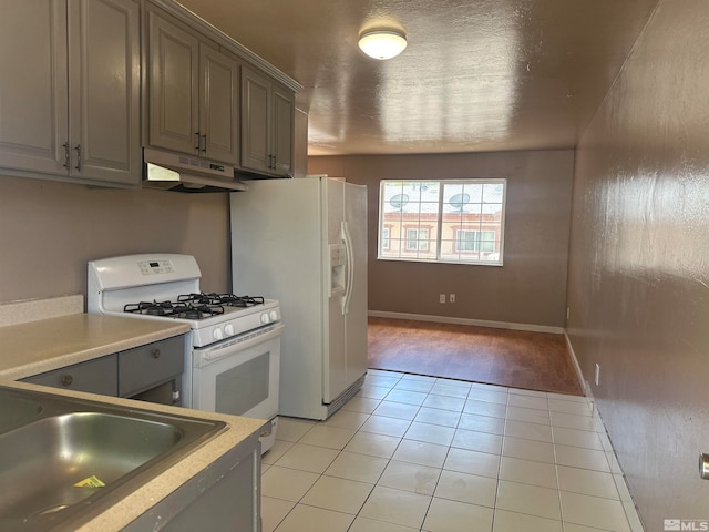 kitchen with sink, light hardwood / wood-style flooring, gray cabinets, and white appliances