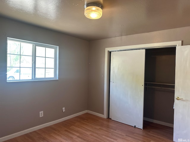 unfurnished bedroom with wood-type flooring and a closet