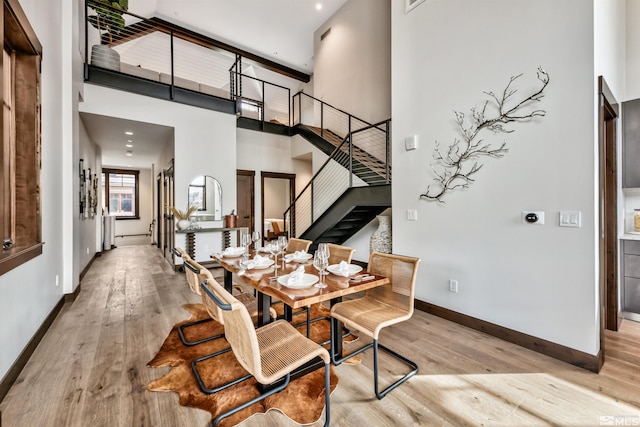 dining space with light hardwood / wood-style flooring and a high ceiling