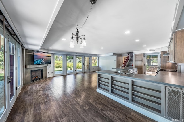 kitchen with stainless steel counters, a high end fireplace, dark hardwood / wood-style floors, sink, and an inviting chandelier