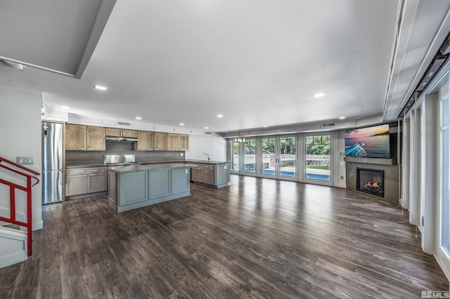 kitchen featuring a kitchen island, dark wood-type flooring, stainless steel fridge, and range