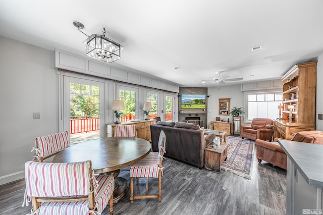 dining space featuring ceiling fan with notable chandelier and dark wood-type flooring