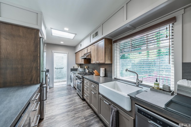 kitchen with a healthy amount of sunlight, dark hardwood / wood-style flooring, stainless steel appliances, and sink