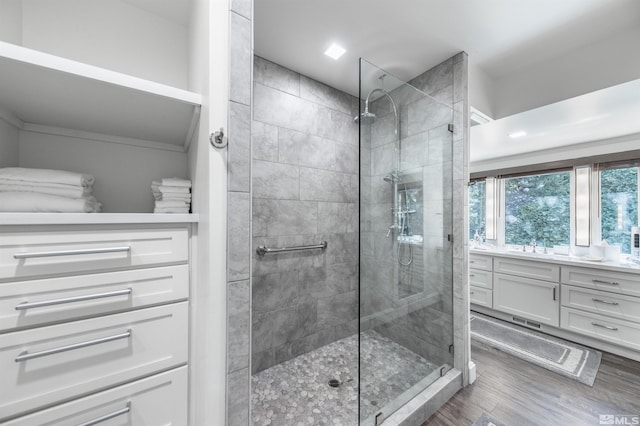 bathroom with a shower with door, hardwood / wood-style floors, and vanity