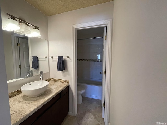 full bathroom with vanity, a textured ceiling, tiled shower / bath combo, tile patterned flooring, and toilet