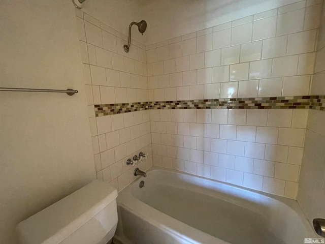 bathroom featuring tiled shower / bath combo and toilet